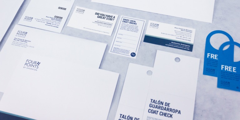 Material impreso de Grupo Regio para Four Points by Sheraton, con papelería corporativa en blanco y azul que incluye sobres, tarjetas, talones y colgadores de puerta, demostrando impresión offset de alta calidad en Cancún.