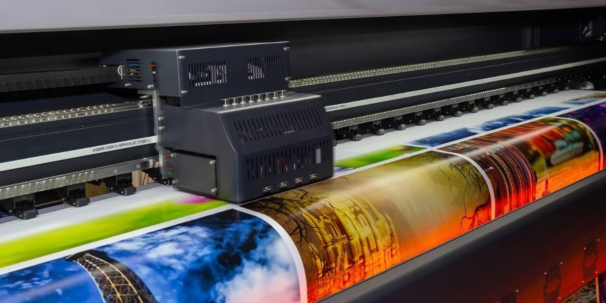 Impresora de gran formato produciendo espectaculares publicitarios a color en alta calidad.