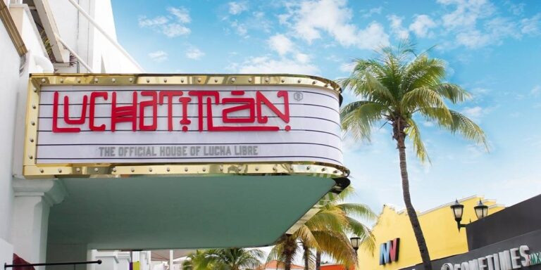 Imagen de letrero luminoso en fachada con la palabra “Luchatitlán” en letras rojas sobre fondo blanco con bordes dorados, acompañado del texto “The Official House of Lucha Libre”, ejemplo de señalética y letreros personalizados de alta calidad producidos en Cancún por Grupo Regio.