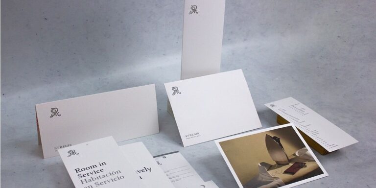 Imagen de papelería corporativa para St. Regis Hotels, con menús, tarjetas y sobres en diseño blanco elegante con tipografía fina y logotipo distintivo, ejemplo de impresión hotelera premium realizada en Cancún por Grupo Regio.