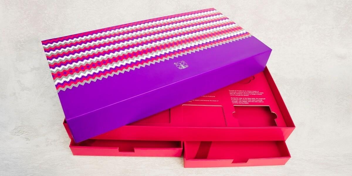 Caja premium en tonos morado y rosa con diseño geométrico, producida por Grupo Regio para presentación exclusiva.