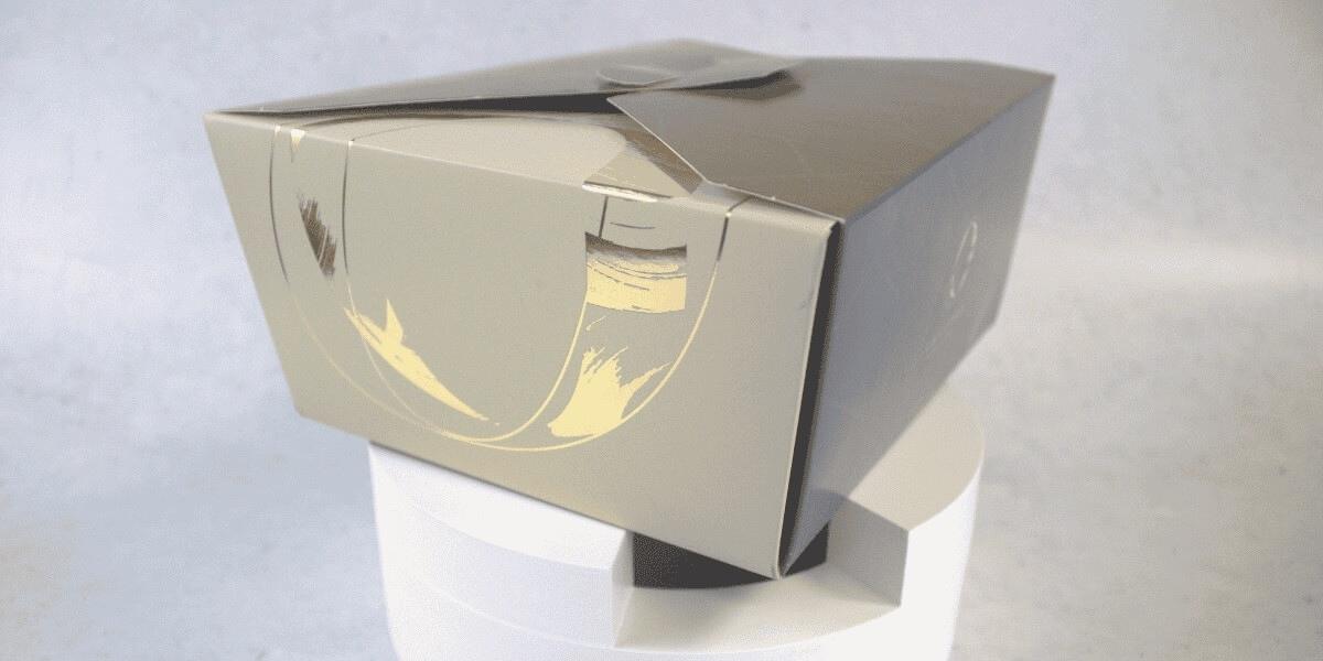 Empaque premium para Orfebre, caja plegadiza con acabados metálicos dorados, diseñada por Grupo Regio para repostería fina.