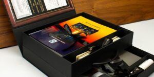 Caja de lujo personalizada con libros, diplomas y lazos negros, producida por Grupo Regio para entregas exclusivas.