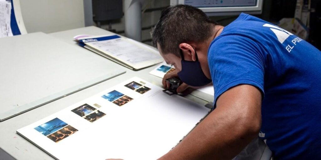 Técnico de Grupo Regio revisando pruebas de color en impresión offset para garantizar calidad en materiales impresos.