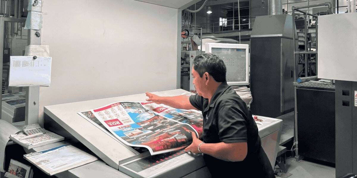 Operador revisando impresión offset industrial en Grupo Regio durante control de calidad de materiales gráficos.