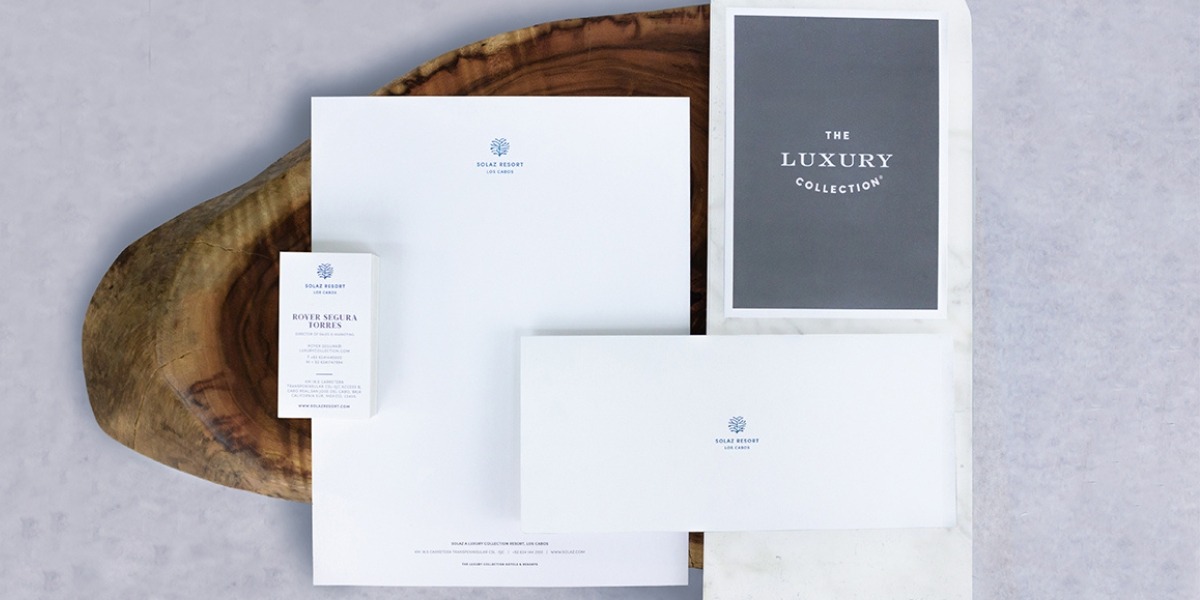 Papelería corporativa impresa por Grupo Regio para The Luxury Collection – Solaz Resort Los Cabos, incluyendo tarjetas de presentación, hojas membretadas, carpetas y sobres en diseño minimalista blanco con detalles en azul, reflejando elegancia en hospitalidad de lujo