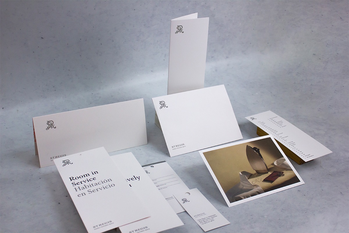 Papelería operativa impresa por Grupo Regio para St. Regis Hotels & Resorts, con menús, colgadores, sobres y tarjetas en diseño minimalista blanco con el monograma SR en gris, reflejando elegancia y lujo en hotelería premium.