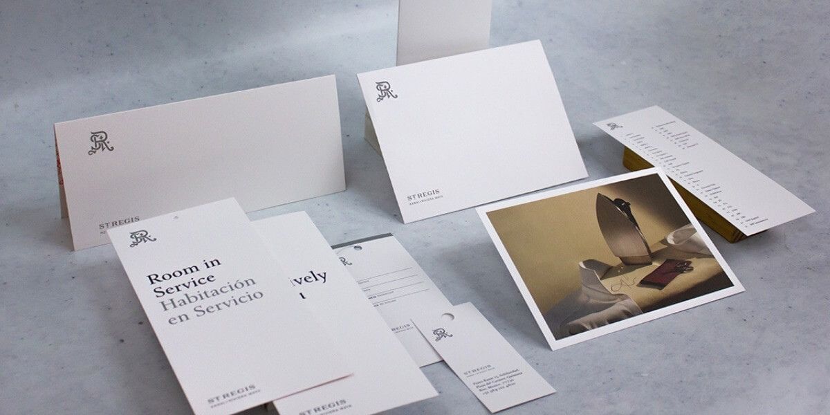 Papelería operativa impresa por Grupo Regio para St. Regis Hotels & Resorts, con menús, colgadores, sobres y tarjetas en diseño minimalista blanco con el monograma SR en gris, reflejando elegancia y lujo en hotelería premium.