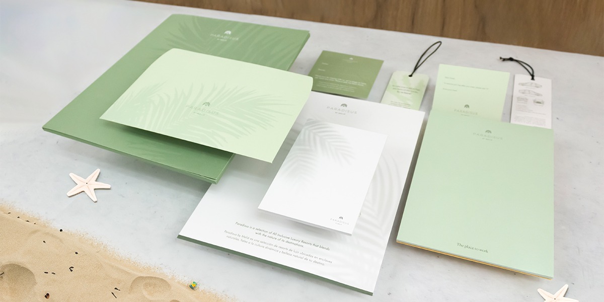 Papelería corporativa impresa por Grupo Regio para Paradisus by Meliá, con carpetas, blocs, colgadores y sobres en tonos verdes con diseños de hojas, transmitiendo frescura y conexión con la naturaleza en hospitalidad de lujo.