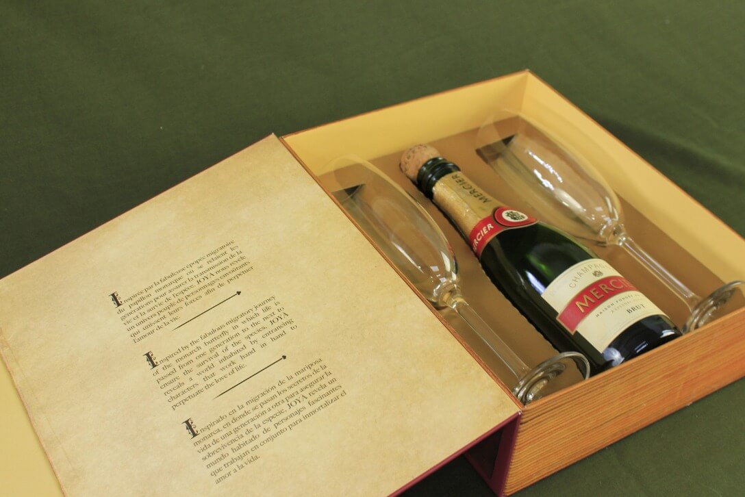 Empaque premium personalizado para botella de champagne con copas, diseñado por Grupo Regio.