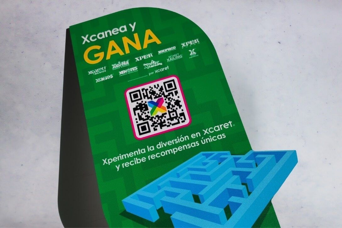 Display publicitario con código QR para promoción de Xcaret, impreso en cartón a color con diseño interactivo.