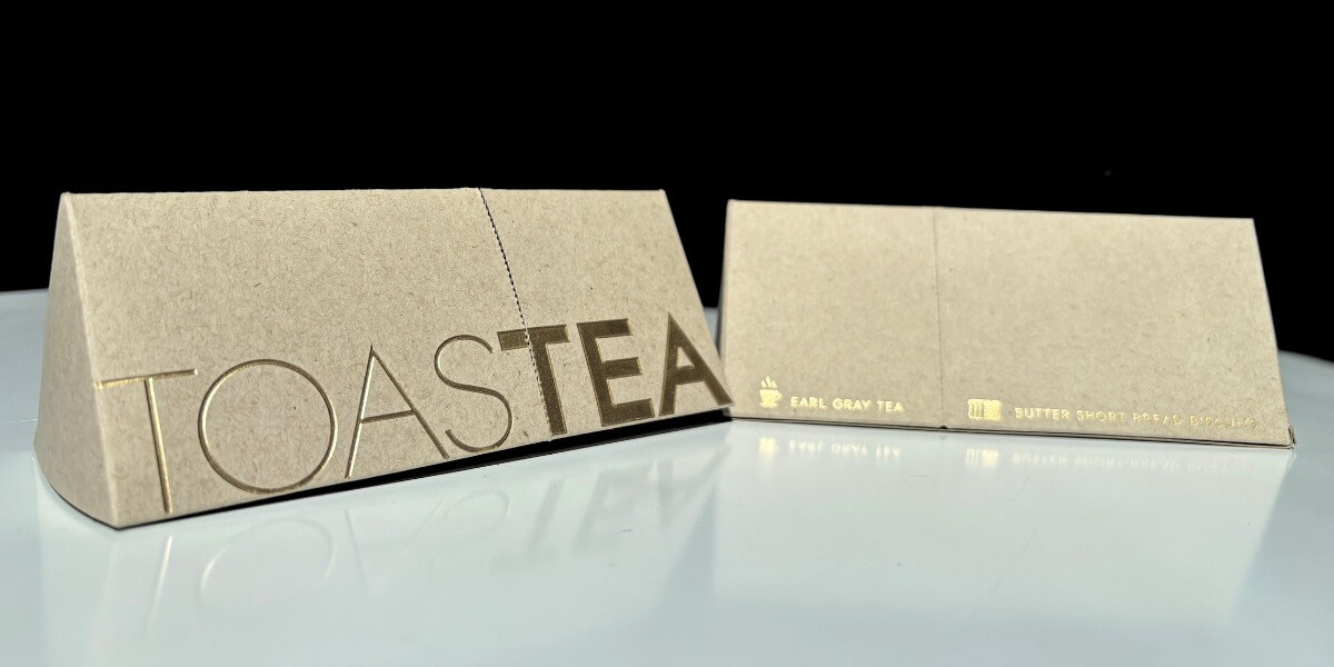 Empaque sustentable de cartón kraft para té gourmet Toast Tea con hot stamping dorado.